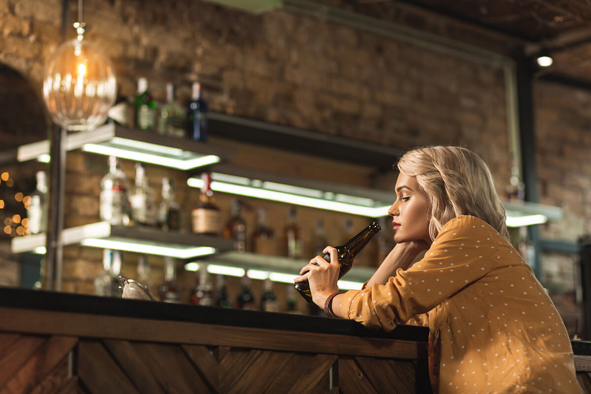 woman with a drink at the bar wonders is alcohol a stimulant