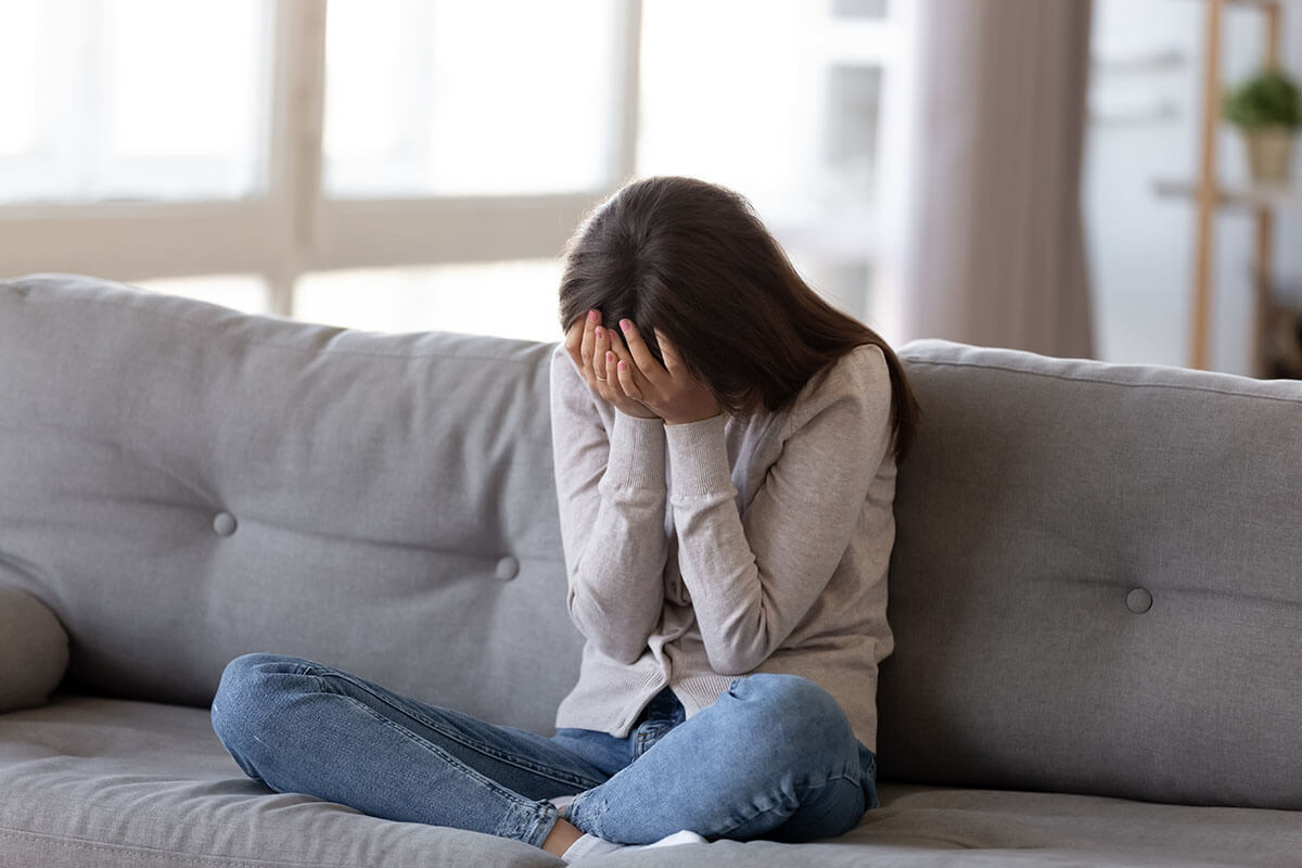 woman with face in hands experiencing heroin withdrawal symptoms