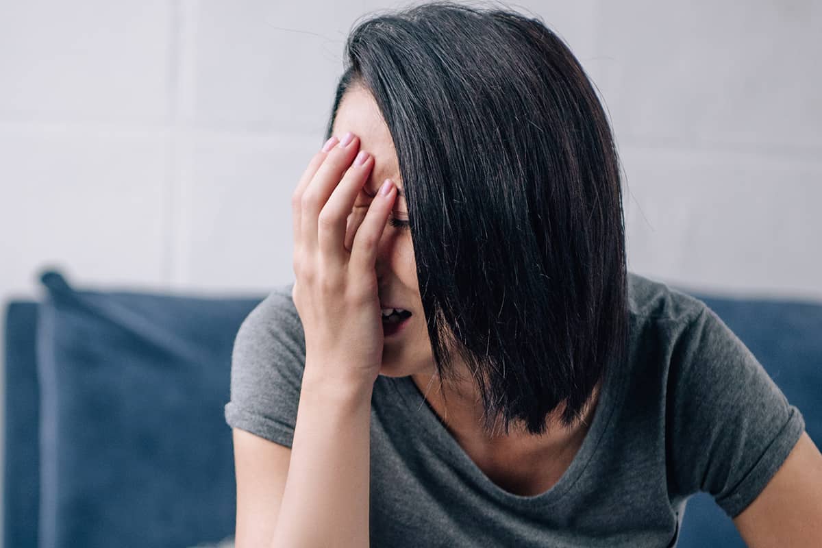 a woman covers her face as she deals with anxiety and addiction